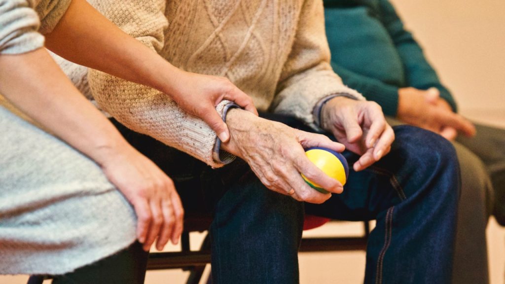 Main d'un vieillard tenant un citron, confortée par une main apaisante.